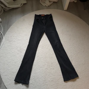 Svarta bootcut jeans från Blue Star - Svarta jeans från Blue Star med klassisk femficksdesign och dragkedja. Modellen har bootcut-ben som ger en snygg utsvängd siluett. Jeansen är tillverkade i ett mjukt denimtyg och passar perfekt för dig som gillar en retroinspirerad look.