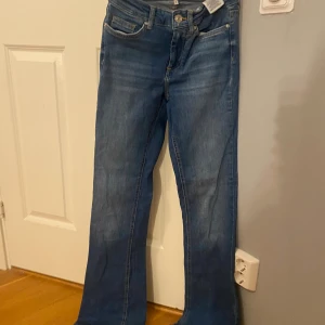 Blå bootcut jeans från ONLY XS - Snygga blå jeans från ONLY i bootcut-modell med hög midja. Klassisk femficksdesign och dragkedja med knapp framtill. Jeansen är i ett mjukt denimtyg och har en lätt utsvängd passform nertill för en trendig look.