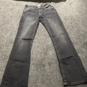 Svarta jeansbyxor från Gina Tricot - Säljer ett par svarta jeansbyxor från Gina Tricot med kontrasterande vita sömmar och snygga fickdetaljer med lock och knapp bak. Klassisk femficksmodell och raka ben. Perfekta till en cool vardagslook.
