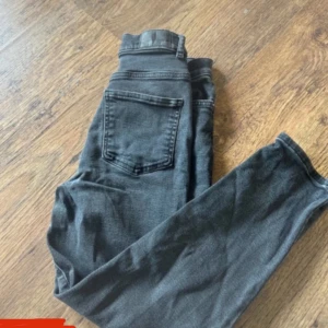 Mörk gråa raka jeans  - Säljer ett par mörkgråa raka jeans. Klassisk femficksmodell med dragkedja och knapp framtill. Jeansen är i stretchigt denimtyg som sitter tight hela vägen ner. Perfekta till sneakers eller boots.