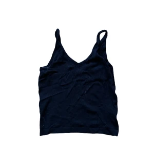 Svart stickad linnetopp - Cubus - En enkel svart stickad linnetopp med smala axelband och v-ringad hals. Perfekt att styla med jeans eller kjol för en clean look. 