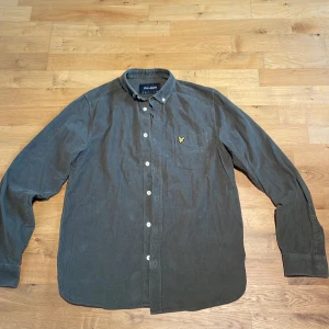 Mörkgrön manchesterskjorta Lyle & Scott S - Snygg mörkgrön skjorta från Lyle & Scott i mjuk manchester. Klassisk button-down krage, bröstficka med gul broderad logga och vita knappar framtill. Perfekt för dig som gillar stilrena detaljer och skön passform. Storlek: S