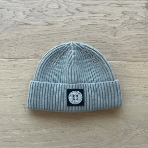 Grå Stone Island Beanie - Säljer denna snygga och sköna Beanie från Stone Island i grå färg. Mössan är Onesize