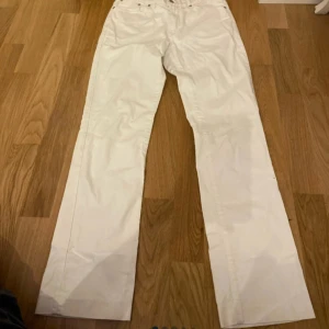 Vita byxor från Gant W30/L32 - Snygga vita byxor från Gant i modellen Dawn med normal midja och regular fit. Byxorna har raka ben och coola detaljer med broderi och stenar på bakfickorna. Perfekta till sommaren och lätta att matcha med allt.