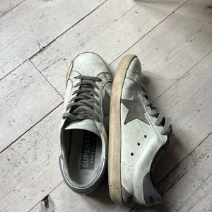 Golden Goose Superstar sneakers, strl 39 - Golden Goose Superstar sneakers i vitt och grått med ikonisk stjärndetalj på sidan. Skriv gärna om ni har frågor och pris kan diskuteras.