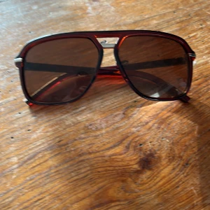 Bruna pilotbågar solglasögon retro - Snygga solglasögon med pilotbågar i transparent brun plast och mörka linser. Klassisk retrostil med metall-detalj vid näsryggen. Perfekta för dig som vill sticka ut med en cool vintage-look.