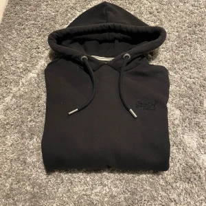 Superdry hoodie  - En svart Superdry hoodie i bra skick storlek M det är bara att skiva vid frågor
