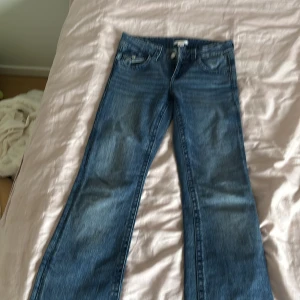 gina young blå bootcut jeans med broderi på bakfickorna  - Snygga blå jeans med bootcut passform och coola broderade detaljer på bakfickorna. Klassisk femficksmodell med knapp och dragkedja framtill. Jeansen har en normal midja och är gjorda i mjukt denimtyg som sitter skönt hela dagen.