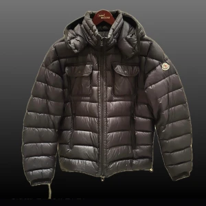 Blå Moncler dunjacka - Mörkblå Moncler Valence Giubotto dunjacka med huva. Jackan har två fickor på bröstet. Jackan är i fint skick och varsamt använd, det enda slitaget är på serietidningen på insidan. Storlek 3, motsvarar M/L
