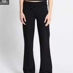 Svarta mjukisbyxor med snörning - Svarta mjukisbyxor med bootcut-stil och snörning i midjan. Byxorna har en avslappnad passform och är perfekta för en chill och bekväm look. Tillverkade i mjukt material som känns skönt mot huden.