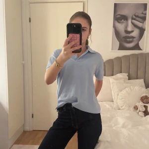 Ljusblå piké från Lacoste - Säljer en ljusblå pikétröja från Lacoste med klassisk krage och korta ärmar. Tröjan har två knappar vid halsen och den ikoniska krokodilloggan på bröstet. 