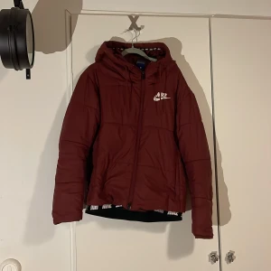 Vinterjacka - Säljer en vinröd vinterjacka från Nike med huva och dragkedja. Snygg och sportig stil som funkar till det mesta. Jackan är använd men i väldigt bra skick!