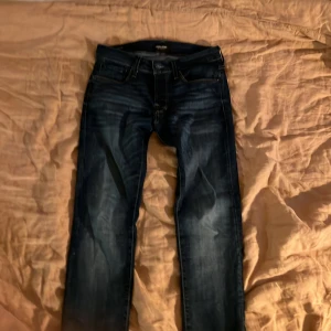 Jack & Jones Slim Glenn jeans blå 29/30 - Snygga mörkblå jeans från Jack & Jones i modellen Slim Glenn. Jeansen har en slim passform, klassisk femficksdesign och är tillverkade i bomullsmix. Perfekta för dig som gillar en smalare siluett och stilrena detaljer.