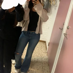 Blå bootcut jeans med hål på knät - Säljer ett par blå bootcut jeans med snyggt hål på ena knät. Jeansen har klassisk femficksdesign och normal passform upptill som blir vidare nertill. Perfekta för dig som gillar en avslappnad och trendig stil. Low waist!!!