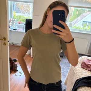 Olivegrön t-shirt från UNIQLO - Använd få gånger men har en liten fläck fram! Stolek XS
