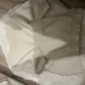 Vit stickad kortärmad tröja - En  vit stickad tröja med korta ärmar och båtringad hals. Tröjan har ribbade kanter vid ärmslut, halsringning och nederkant. Perfekt för lager-på-lager och passar till många olika outfits. Från Gina tricot young (158/164, passar XSS XS S)