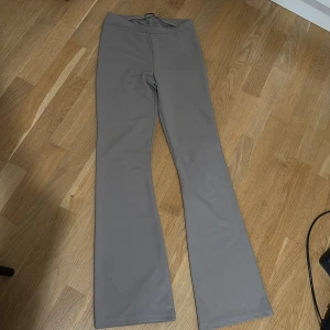 Grå bootcut byxor med stretch - Snygga grå bootcut byxor med skön stretch och hög midja. Perfekta för dig som gillar en stilren look med lite utsvängda ben. Materialet känns mjukt och följsamt, vilket gör dem riktigt bekväma att bära hela dagen.