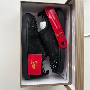 Svarta sneakers med nitar från Sangenar - Säljer ett par svarta sneakers från Christian Sangenar med coola svarta nitar på tån och sidorna. Skorna har snörning, platt sula och är gjorda i mocka och skinn. Röd undersula med logga ger en extra touch. Perfekta för dig som vill sticka ut.