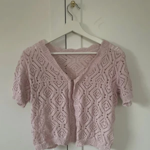 Ljusrosa stickad blus med v-ringning - Supersöt ljusrosa stickad blus med korta ärmar och v-ringning. Denna blus har stickats av familjemedlem!!