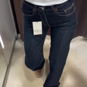 Mörkblå raka jeans från Zara - Snygga mörkblå jeans från Zara med klassisk femficksdesign och kontrastsömmar. Modellen har rak passform och normal midja, vilket ger en avslappnad men stilren look. Perfekta till sneakers eller boots och tillverkade i slitstarkt denimtyg.