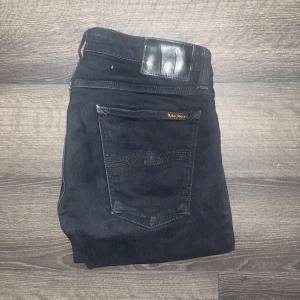 Nudie jeans  - Säljer ett par svarta Nudie Jeans Skinny Lin i storlek 32/34. Modellen är skinny med smal passform och raka ben. Materialet är 98% bomull och 2% elastan för extra stretch. Klassisk femficksdesign och svart läderpatch bak.  Midja 39cm, längd 107cm. Ifall det inte finns någon bild i annonsen där jag bär plaggen jag säljer så är det för att jag ej kan ha storleken heller passformen, så kolla måtten för storlek och googla på modellnamnet för passform 😉24
