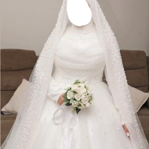 Vit långklänning med pärldetaljer - Brudklänning till salu 💍Drömmig vit långklänning med hög hals och långärmade ärmar, täckt av pärldetaljer och ett matchande slöja. Perfekt för dig som vill ha en klassisk och lyxig look , Elegant och modest brudklänning perfekt för hijabi-brudar. Använd endast en gång – i mycket fint skick! Långärmad design med vacker spets och täckande stil. Storlek: M  Färg: Pärlvitt Längd: Pass medellängd 