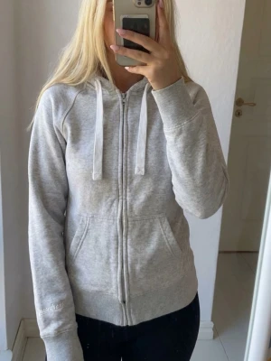 Russemerch zip hoodie Grå - Säljer denna russe zip hoodie i storlek S. Har använts ett fåtal gånger. Tjejen på sista bilden är 165cm lång. Nypris ligger just nu på ca750kr jag säljer denna för 450kr. Har ni frågor eller funderingar är det bara att skriva och fråga. Mvh Liam!😁
