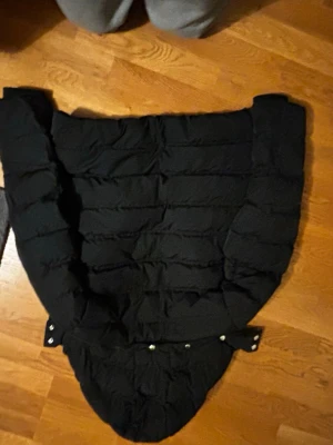 Svart pufferjacka från GANT - Svart pufferjacka från GANT med avtagbar huva och dragkedja framtill med GANT-logga. Jackan har långa ärmar och quiltad design som ger en schysst look. Perfekt för dig som vill ha en varm och stilren jacka med streetkänsla.