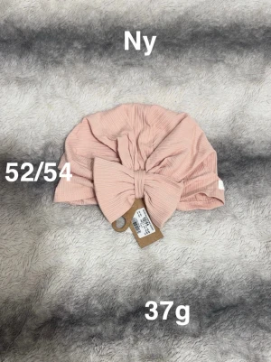 Rosa ribbad turban med rosett - Säljer en söt turban i ljusrosa ribbad bomull med stor rosett framtill. Perfekt accessoar för att lyfta din look och ge en trendig touch. Turbanen är mjuk och lätt, väger endast 37g och passar dig som gillar detaljer.🌸 Ny. Storlek 52/54