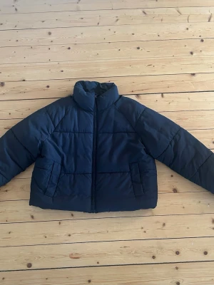 Svart pufferjacka från Monki - Svart pufferjacka från Monki i storlek S. Jackan har hög krage, två fickor framtill och stängs med dragkedja🤎