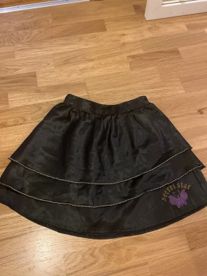 Svart glittrig kjol från Secret Star 140 - Säljer en svart glittrig kortkjol från Secret Star i storlek 140. Perfekt nu till nyår!!