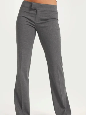 Grå kostymbyxor - Snygga grå kostymbyxor med bootcut-snitt och låg midja. Byxorna har en klassisk rak passform och är tillverkade i ett mjukt material som ger en stilren look. 