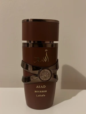 Lattafa Asad Bourbon parfym - Snygg och unik parfymflaska från Lattafa med namnet Asad Bourbon. Perfekt för dig som vill sticka ut med din stil. Volym och ingredienser framgår ej på bilderna. 35ml kvar på den!