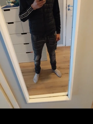 Dsquared2 mörka jeans med dragkedja - Säljer ett par snygga dsquared2 jeans i mörk tvätt med slitningar och dragkedjedetalj vid fickan. Modellen är slim och har en tapered passform som sitter tajt vid benen. Jeansen har klassisk femficksdesign och är tillverkade i stretchig bomull för skön komfort.