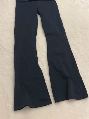 Mörkblå bootcut byxor från RYVLS - Snygga mörkblå bootcut byxor från RYVLS med broderad text 'Stockholm' på linningen. Byxorna har en mjuk och stretchig känsla, perfekt för dig som gillar bekväma och trendiga plagg. Passar dig som vill ha en cool och avslappnad stil.🫰🏼Stretchiga - därav passar de även större storlekar.