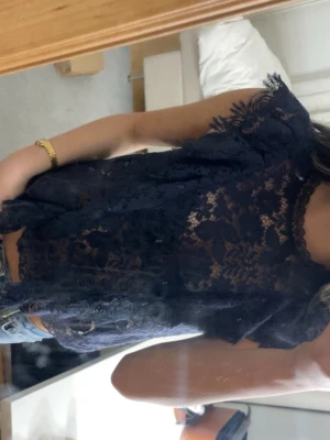 Mörkblå spetsblus från Zara - Säljer en mörkblå blus från Zara. Blusen är helt i spets med blommigt mönster och har korta ärmar med fina spetsdetaljer vid kanterna. Jätte snygg och trendar finns ej att köpa längre!