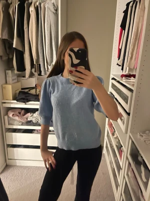 Ljusblå stickad tröja med puffärm - Superfin ljusblå stickad tröja med puffiga halvlånga ärmar och rund halsringning. Perfekt för dig som vill ha en söt och enkel look med lite extra volym på axlarna. Skön och mjuk känsla, passar till både jeans och kjol.