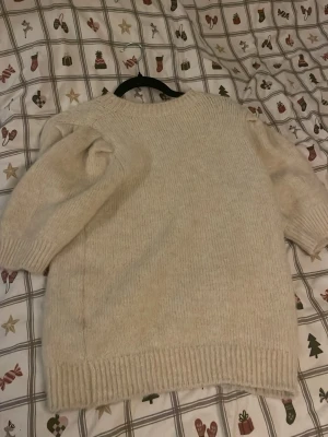 Beige stickad tröja med puffärm - Säljer en beige stickad tröja med puffade axlar och rund hals. Tröjan har ribbade muddar vid ärmslut och nederkant, den är jättemjul och skön. Nypris 500 så säljer för definitivt billigare. Använd endast 1-2 gånger