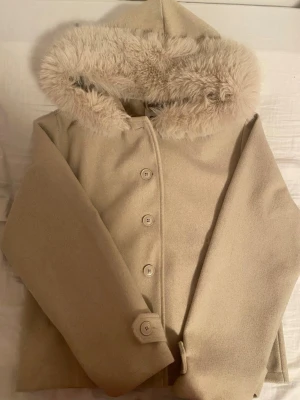 Beige kappa med fuskpäls från Gina Tricot - Säljer en beige kappa från Gina Tricot i storlek M. Jackan har en fluffig fuskpäls. Den är köpt för nån månad sen och använd jätte lite. som helt ny. helt slutsåld på hemsidan!