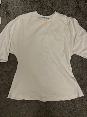 Vit oversized t-shirt från 157 - Enkel vit t-shirt från 157 i oversized modell. T-shirten har rund halsringning och korta ärmar. Tillverkad i mjukt material som känns skönt mot huden. Perfekt till jeans eller shorts för en clean look.