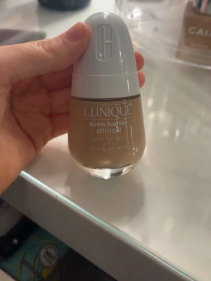 Clinique Even Better Clinical Foundation - Clinique Even Better Clinical serum foundation med SPF 20. Kommer i en rund glasflaska med vit pump och lock. Färgen är medium beige och formulan är flytande, perfekt för en naturlig finish. Enkel att applicera med pumpen och passar dig som vill ha jämn hudton.