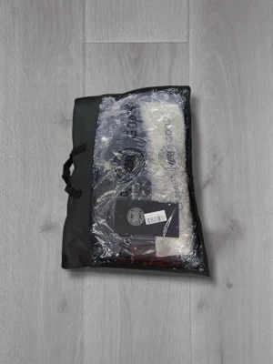 Svart dunjacka från Canada Goose Wyndham med röd bage - Svart dunjacka från Canada Goose med avtagbar huva och pälsdetalj. Jackan har ett klassiskt märke på ärmen, knappar framtill och en quiltad design. Perfekt för kalla dagar och har en snygg, stilren look som funkar till många outfits. Pris kan diskuteras vid snabba affärer