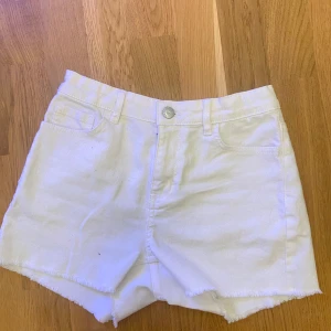 Vita jeansshorts från Lindex - Snygga vita jeansshorts från Lindex med hög midja och rå kant nertill. Klassisk femficksmodell med knapp och dragkedja framtill. Perfekta för sommaren och riktigt fräscha till en chill outfit. Materialet är stadigt denim i bomull.