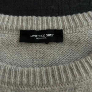 Beige kashmirtröja från Lawrence Grey - Supermjuk och lyxig beige stickad tröja från Lawrence Grey i 97% kashmir och 3% ull. Klassisk rund halsringning, ribbade muddar och långärmad modell. Perfekt för dig som vill ha en stilren och bekväm look. Priset är ej hugget i sten 🪨 