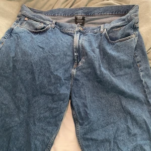 Blåa jeans från Sweet Skateboards - Baggy blå jeans från Sweet Skateboards med klassisk femficksdesign och broderad logga på fickan. Jeansen har en loose passform och är tillverkade i slitstarkt bomullsjeans. Perfekta för dig som gillar streetwear och skate-stil.