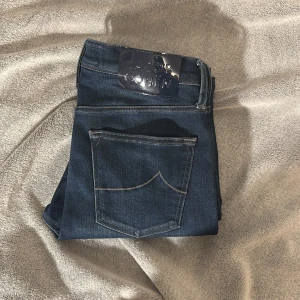 Mörkblå jeans från Jacob Cohën - Snygga mörkblå jeans från Jacob Cohën med klassisk femficksdesign och kontrastsömmar. Jeansen har en tydlig logopatch bak i metallic och dragkedja framtill. Materialet är mjukt denim i bomull med en stilren look.