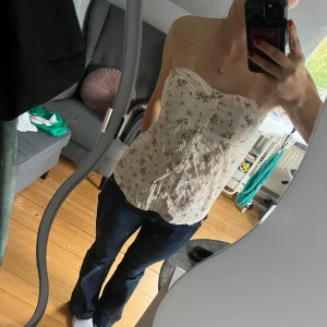 Blommig tubtopp från Fishbone - Supersöt tubtopp från Fishbone i ljusgul med små rosa och vinröda blommor. Toppen har knappar framtill och broderade detaljer som ger en romantisk vibe. Perfekt till jeans eller kjol för en somrig look.