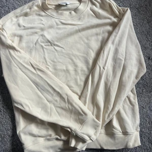 Ljusgul sweatshirt från Monki - En stilren gul sweatshirt från Monki med rund halsringning och ribbade muddar vid ärmslut och nederkant. Perfekt för en avslappnad look och enkel att matcha med jeans eller kjol.