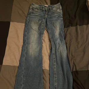 Blå bootcut jeans från Gina Tricot - Snygga blå bootcut jeans från Gina Tricot i storlek 158. Jeansen har coola detaljer med broderade bakfickor och kontrastsömmar. Klassisk femficksmodell i jeansmaterial med låg midja och utsvängda ben. Perfekta för dig som gillar retro vibe!