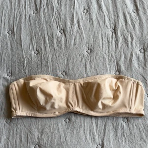 Oanvänd Beige bandeau bh från Wacoal - Snygg bandeau bh från Wacoal i beige färg. Stilren och enkel design utan axelband, med hakknäppning bak. Tillverkad i mjukt och stretchigt material som sitter skönt mot huden. Står storlek 75B men skulle säga den är en storlek mindre i kupan🫶🏻